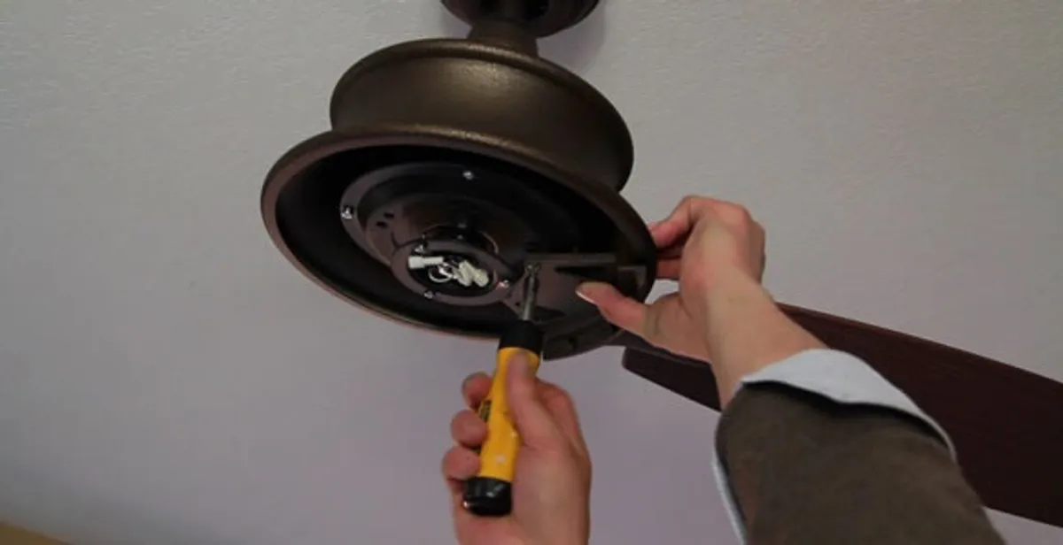 Electrician installing ceiling fan mounting bracket and fixture in Aurora, CO
